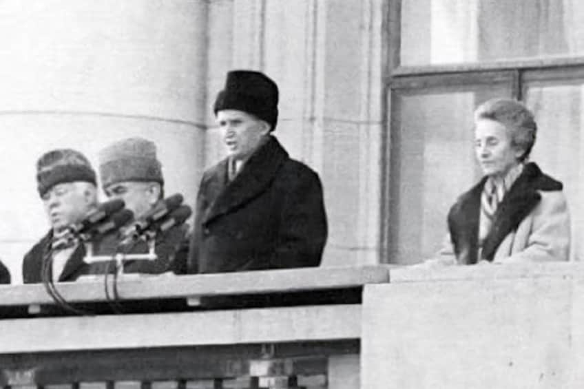 A historical event with individuals at a podium, a building facade, and a window in the background. 4