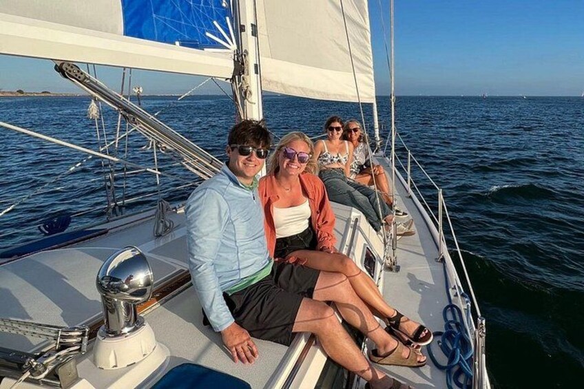 A sailboat with people on deck, a clear sky, and calm sea. 2