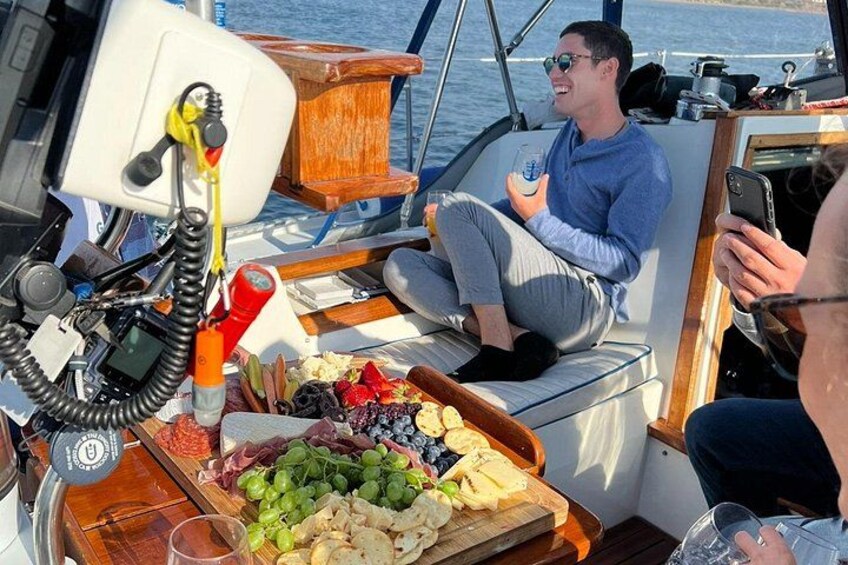 Una persona en un bote con una bandeja de uvas, queso y galletas. 2