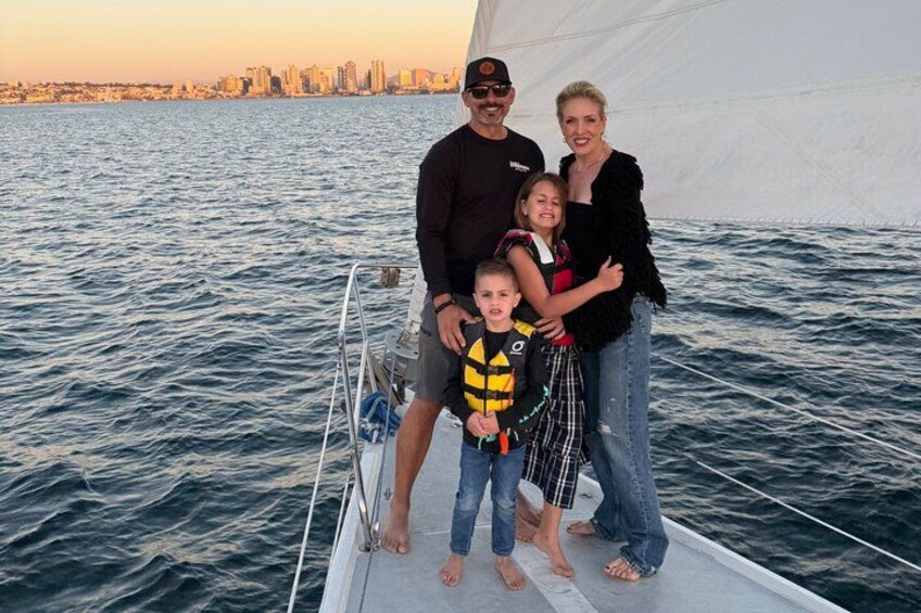 Una familia en un velero, con el horizonte de una ciudad al fondo. 5