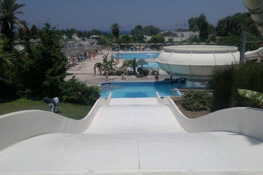 En vandpark med en stor swimmingpool, en vandrutsjebane og et strandområde. 3