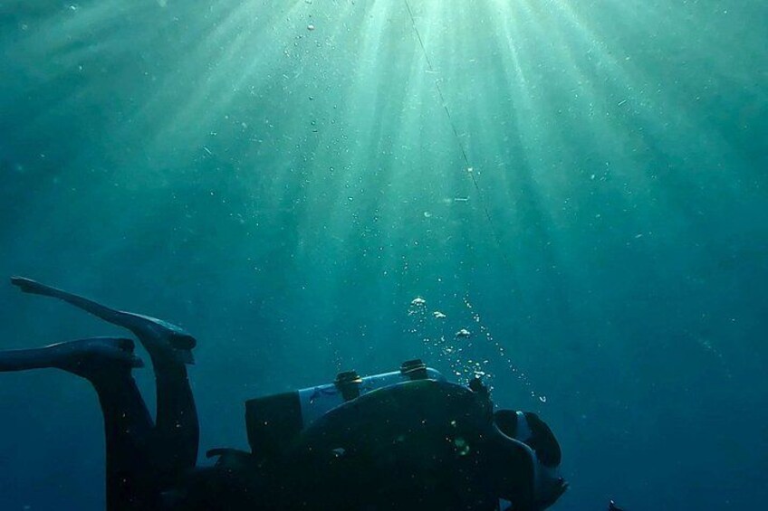 A diver underwater with sunlight rays penetrating the water. 3
