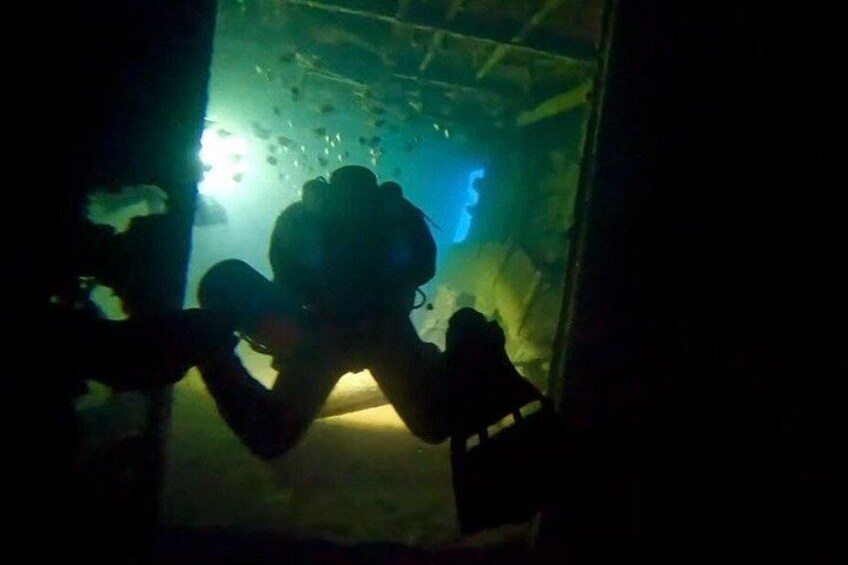 A diver in a dark underwater environment with visible bubbles and a light source. 5