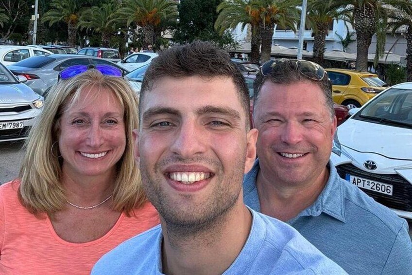 Three people standing in a parking lot with cars and palm trees in the background. 4