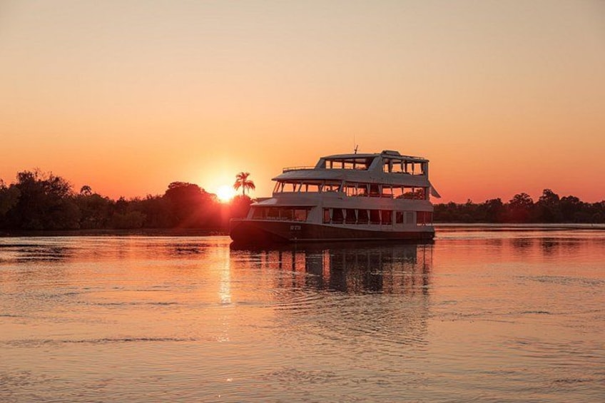 A white boat with a cabin on the water during sunset. 1