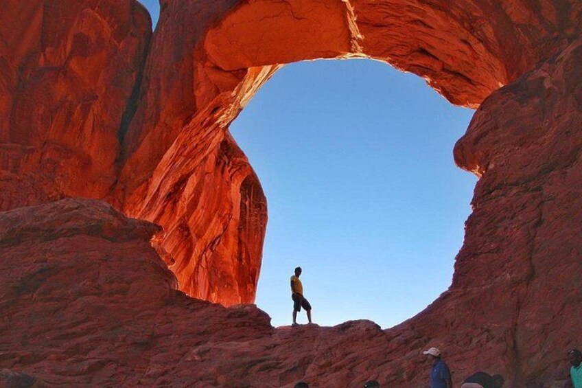 A person standing in a natural rock arch formation. 5