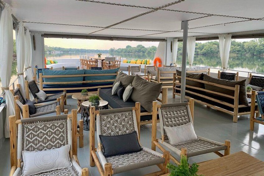 Un espace extérieur aménagé avec des meubles en bois et des coussins, offrant une vue sur une étendue d  ’eau. 3
