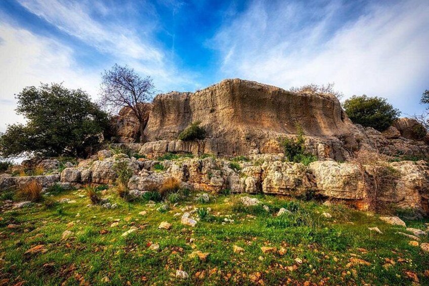 A rocky outcrop with sparse vegetation and a clear sky. 2