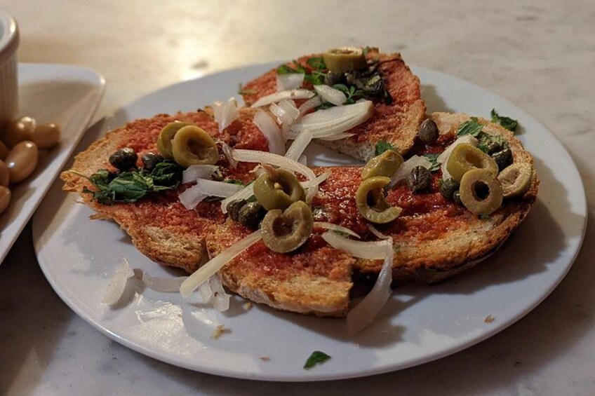 Two slices of pizza topped with olives, onions, and greens on a white plate. 5