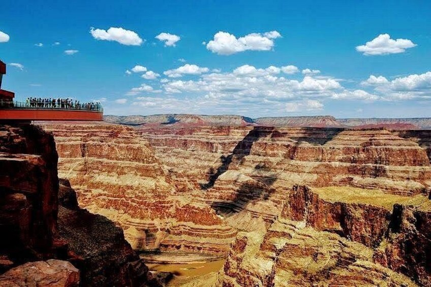 A canyon with layered rock formations and a viewing platform with people. 2