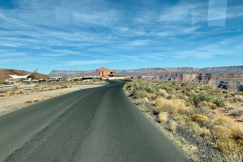 A road curving through a desert landscape with sparse vegetation and distant mountains. 3