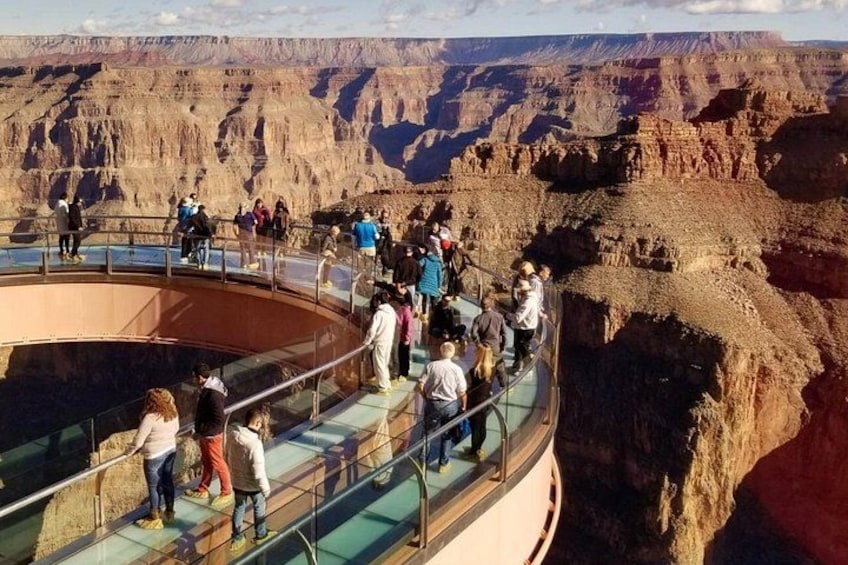 A glass observation deck with visitors overlooking a canyon. 1