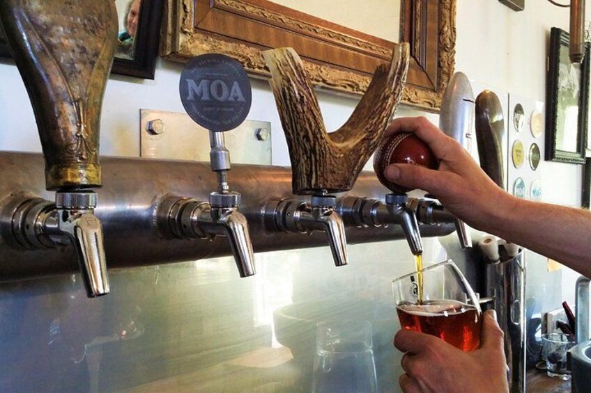 Un grifo con una etiqueta que dice 'MOA' y una persona sirviendo cerveza en un vaso. 2