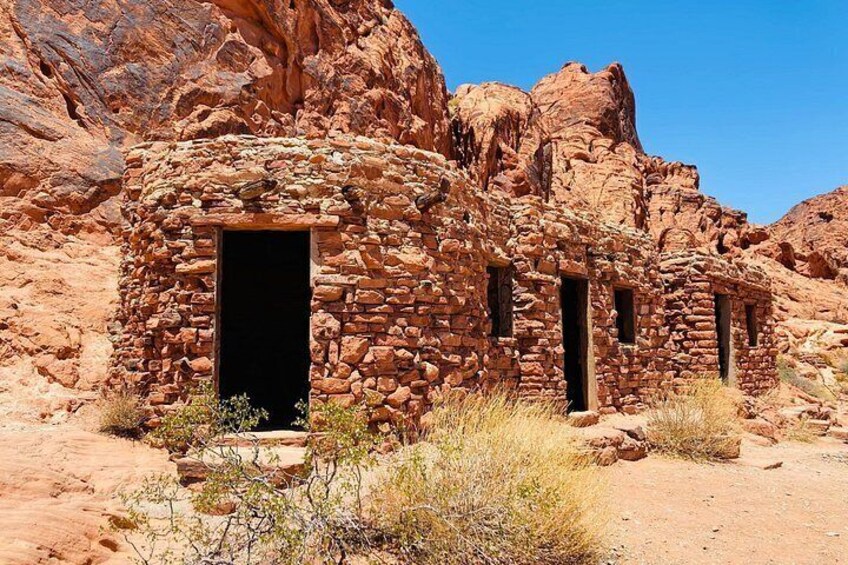 A stone structure with an open doorway, surrounded by desert terrain and rocky cliffs. 3