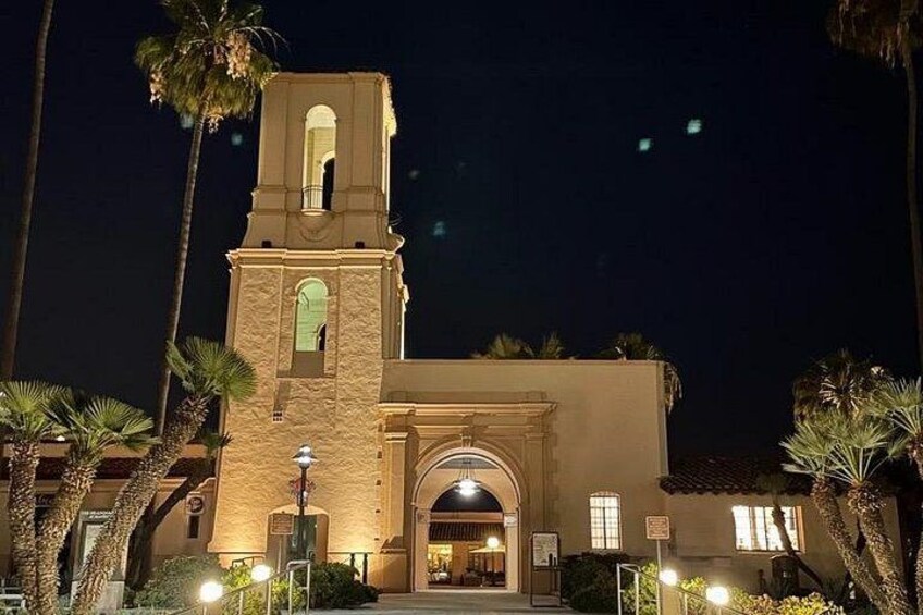 A church with a bell tower, palm trees, and a well-lit entrance. 2