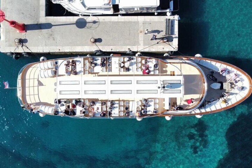 An aerial view of a boat docked at a pier with people on board and on the pier. 2