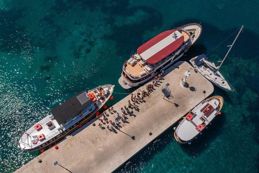 A pier with multiple boats docked, clear turquoise water, and a sandy dock. 2