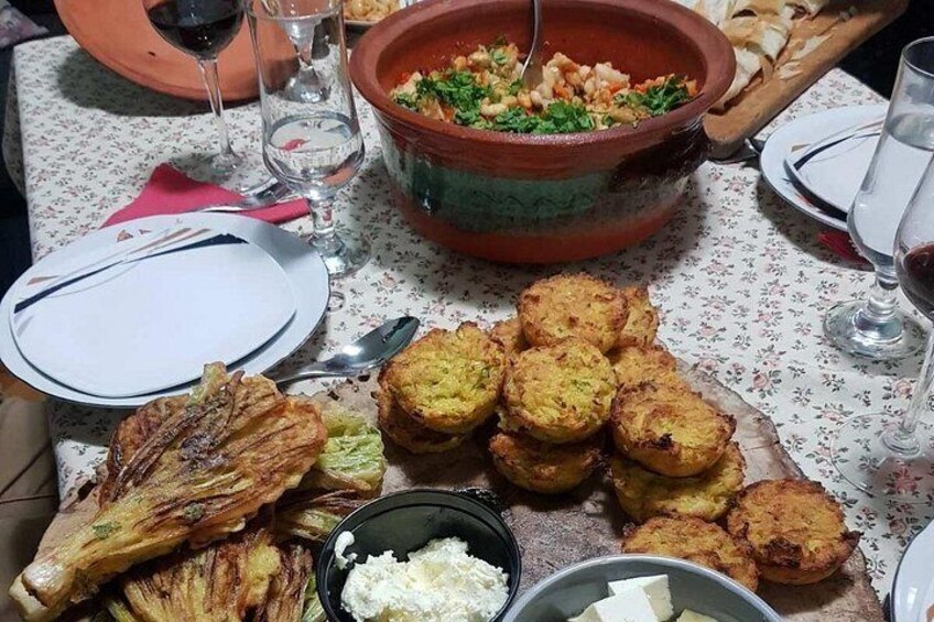 A table with a large clay pot, fried food, and a bowl of white sauce. 2