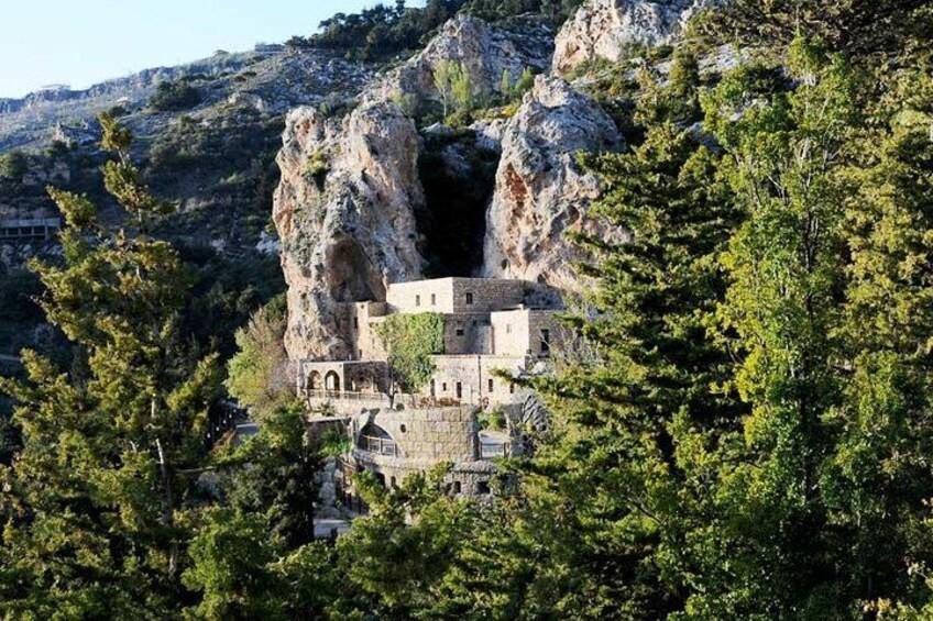 A monastery nestled in a rocky gorge surrounded by trees. 1