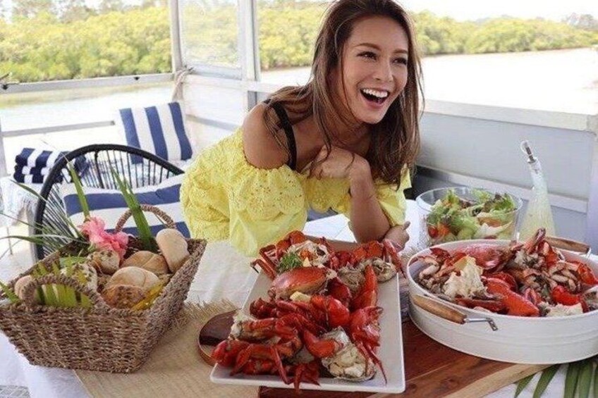 A person at a table with a basket of eggs, a plate of cooked lobsters, and a bowl of salad. 4