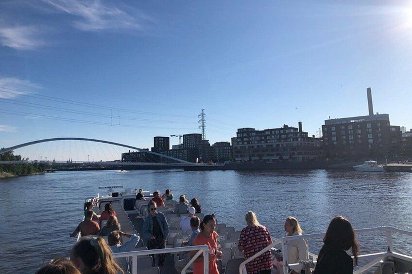Eine Gruppe von Menschen auf einem Boot, eine Brücke und Gebäude im Hintergrund. 2