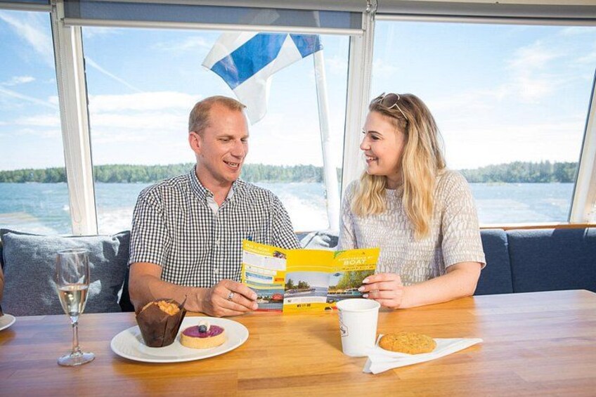 Zwei Personen sitzen an einem Tisch mit einem Buch, einem Weinglas und einem Teller mit einem Muffin und einem Krapfen. 3