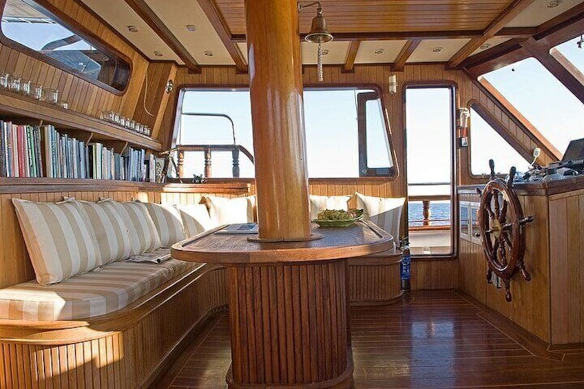 Un interior de madera con una mesa central, estanterías y un volante. 3