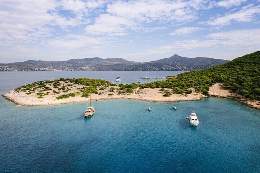 A coastal landscape with boats anchored near a small island. 4