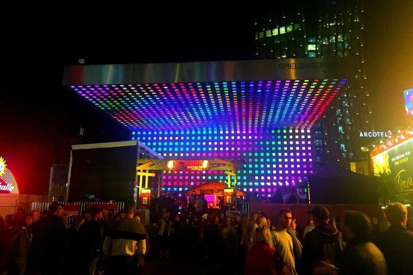 A brightly lit stage with colorful LED lights and a crowd of people in front. 4