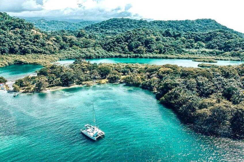 A boat on turquoise waters surrounded by lush green hills. 1