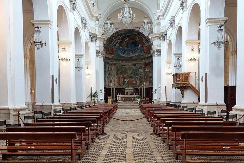 L’intérieur d’une église désertée, avec des rangées de bancs, un grand autel et une fresque détaillée au plafond. 2