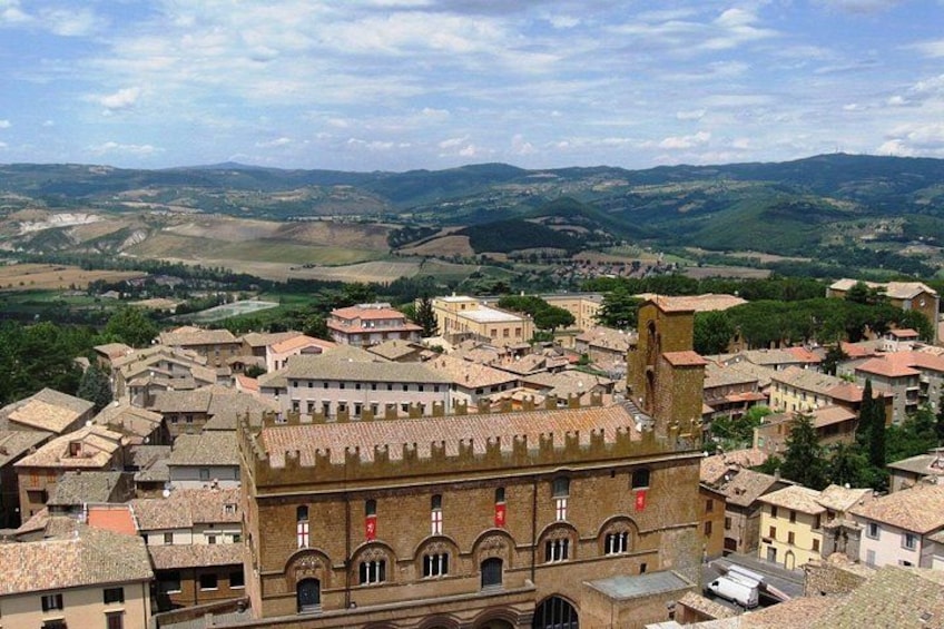 A town with historic buildings, a prominent tower, and rolling hills in the background. 2