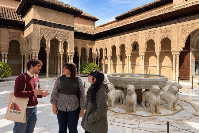 A courtyard with arches, a fountain, and a group of people. 1