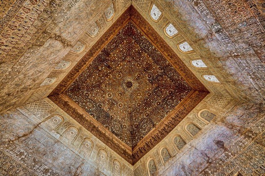 An ornate ceiling with intricate geometric patterns and a central medallion. 4