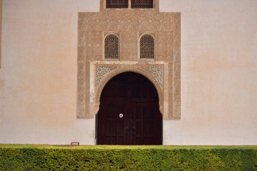 A building with a large arched doorway, intricate geometric patterns, and a small window above the door. 5