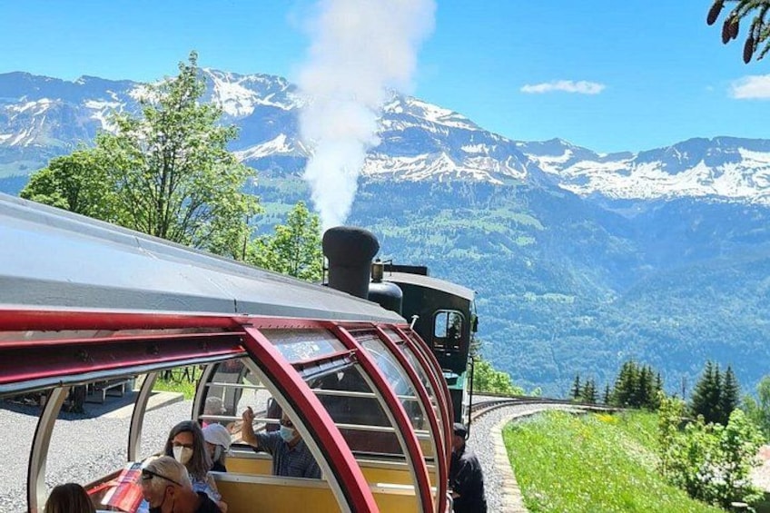 A steam train with passengers, a mountainous landscape, and a clear sky. 4