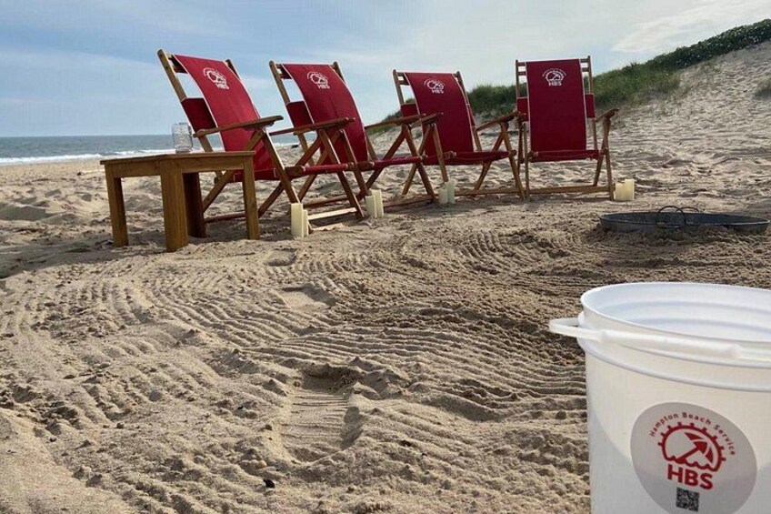 A sandy beach with red beach chairs and a white bucket with a logo. 3