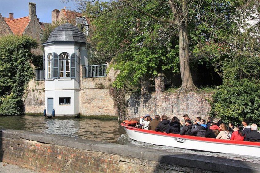 A boat with passengers, a small tower-like structure, and a stone wall with trees. 4