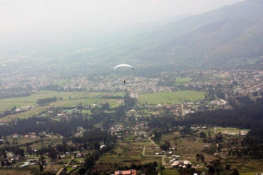 Iemand paraglidet boven een stad omringd door heuvels. 3