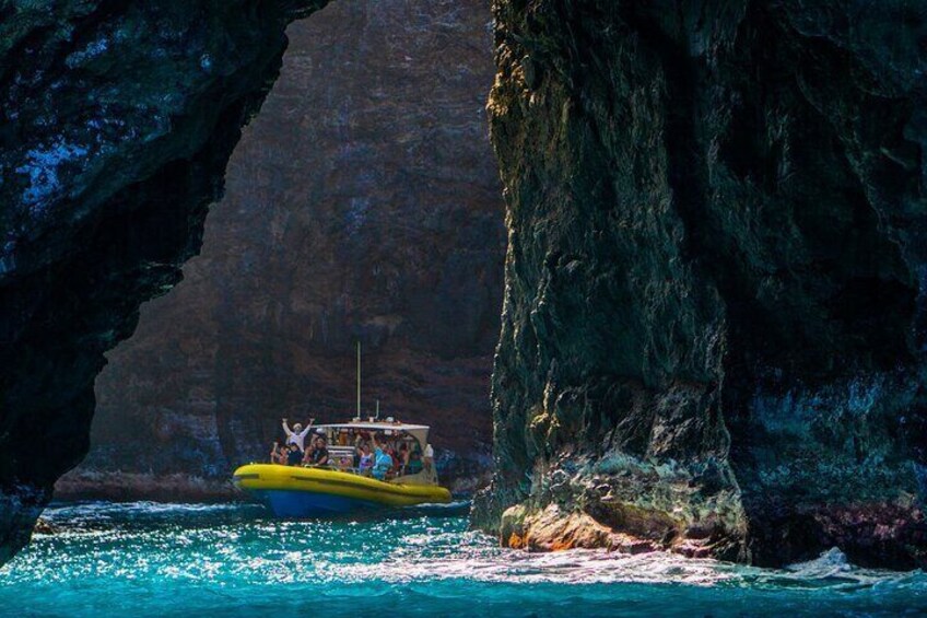 A yellow boat with passengers navigating through a narrow waterway between rocky cliffs. 1