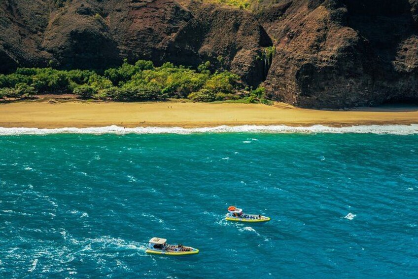 A beach with clear turquoise water, a sandy shore, and rocky cliffs in the background. 2