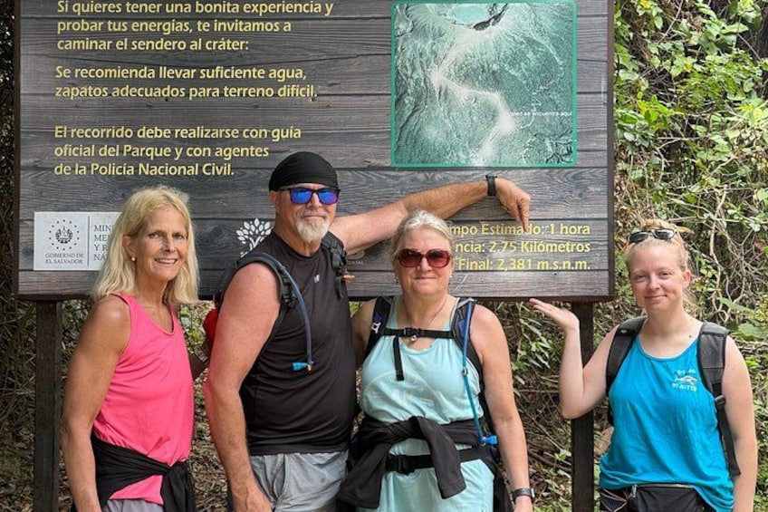 A group of people standing in front of a sign with hiking information. 1