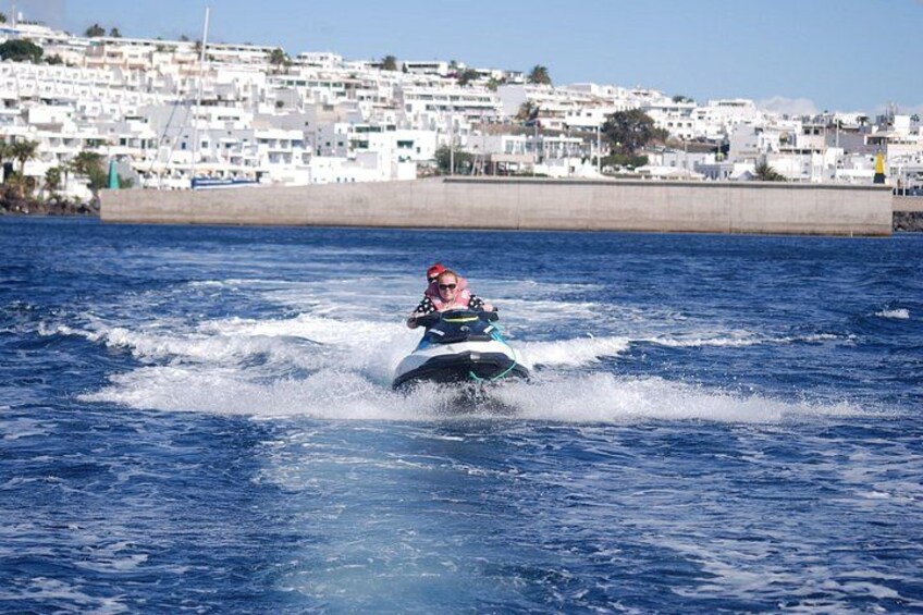 A person jet-skiing on a body of water with a coastal town in the background. 1