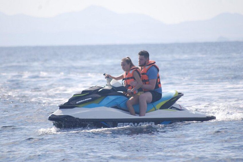 Two people on a jet ski in the water with mountains in the background. 4