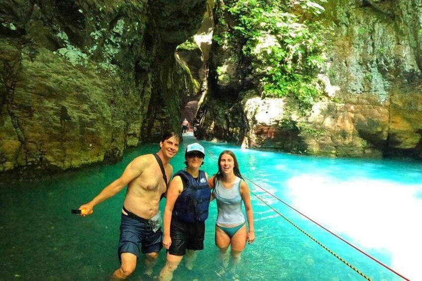 Une grotte avec une piscine aux eaux d’un bleu limpide, un pont de corde et des parois rocheuses. 2