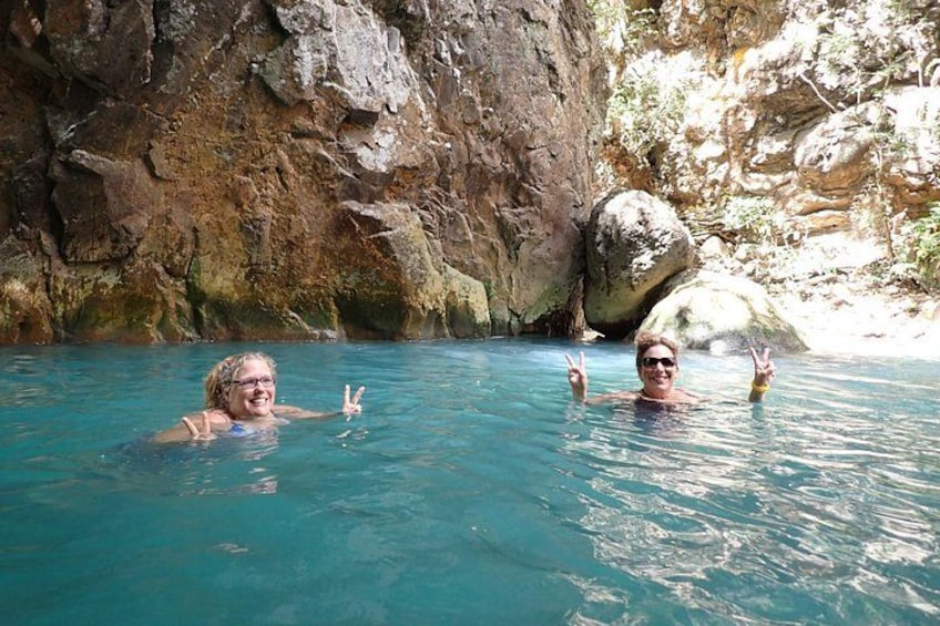 Deux personnes dans une piscine à l’eau cristalline, avec des falaises rocheuses en arrière-plan. 5