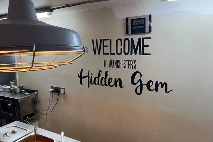 A wall with the text 'WELCOME TO MANCHESTER'S Hidden Gem' and a clock. 4