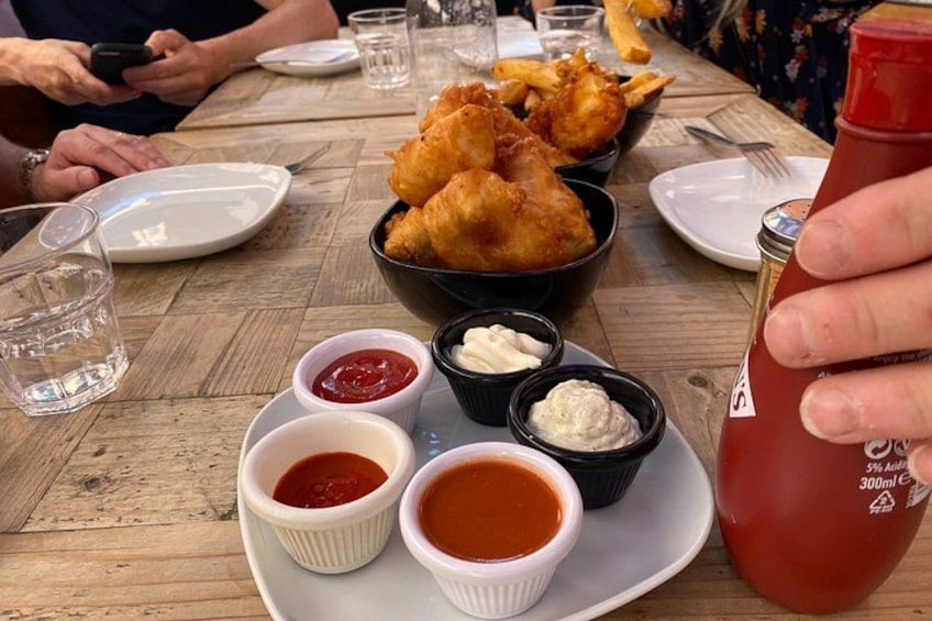 A wooden table with food, including fried items and dipping sauces. 5