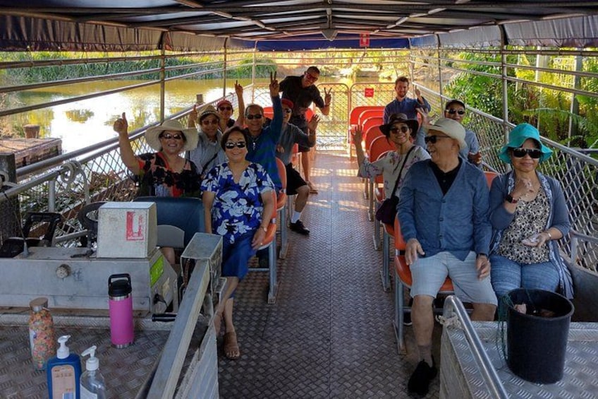 A group of people on a boat with a metal railing and a canopy overhead. 1