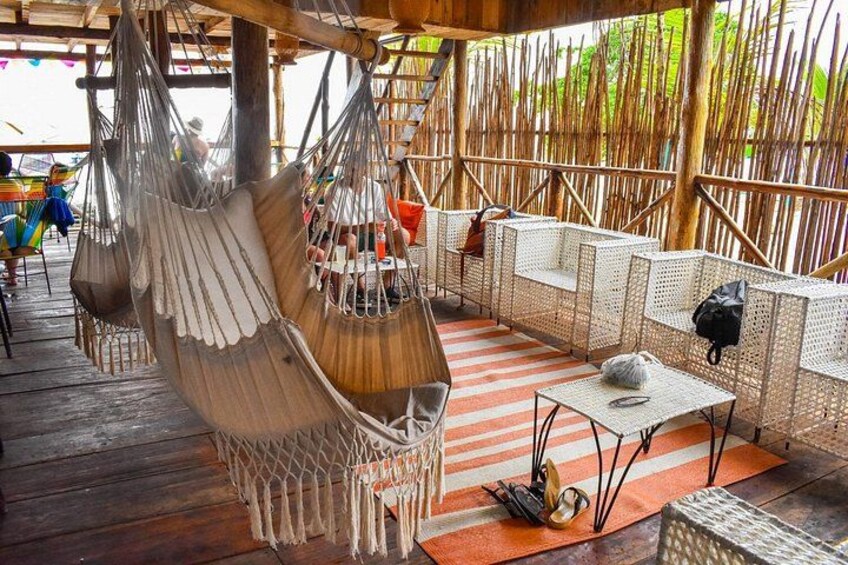 A wooden deck with hanging hammocks, wicker furniture, and a striped rug. 5